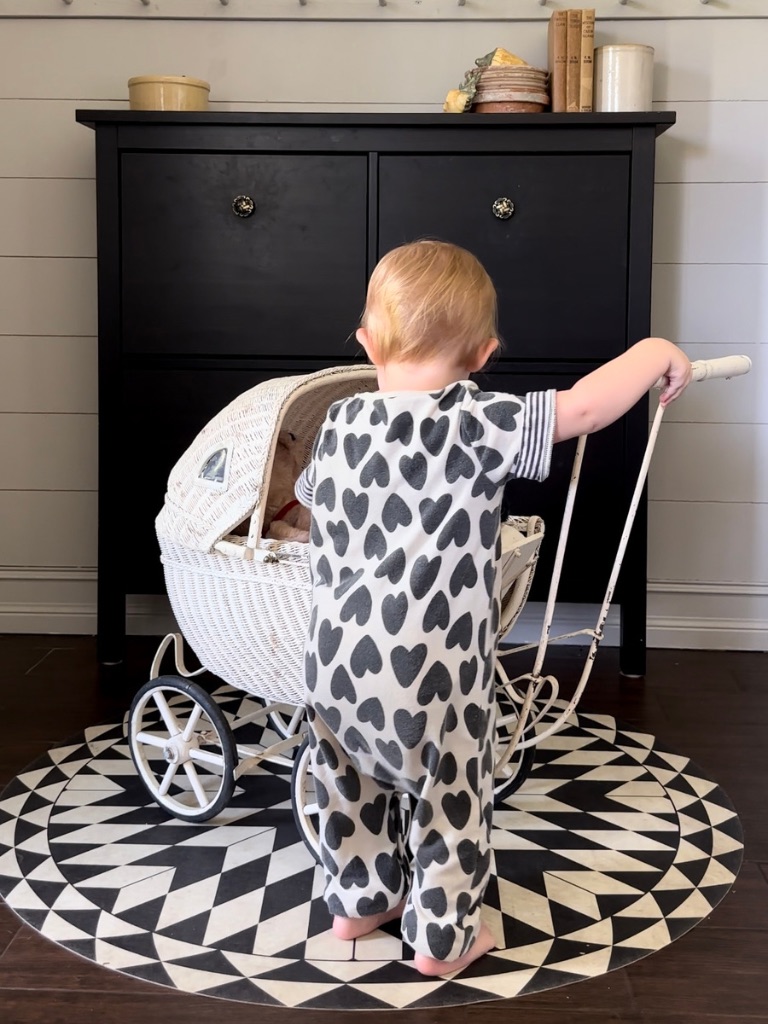 Toddler playing with a vintage pram on a black and white vinyl FloorFlat in the entry