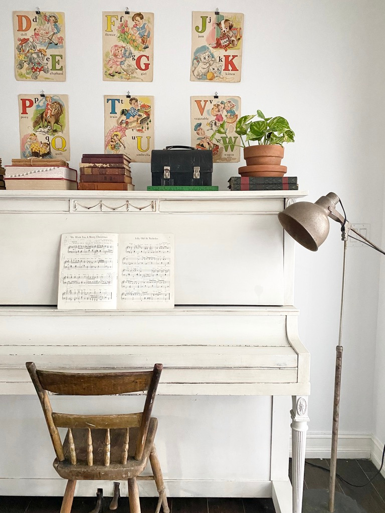 An antique piano styled with vintage book pages, vintage book bundles, and a vintage lunchbox