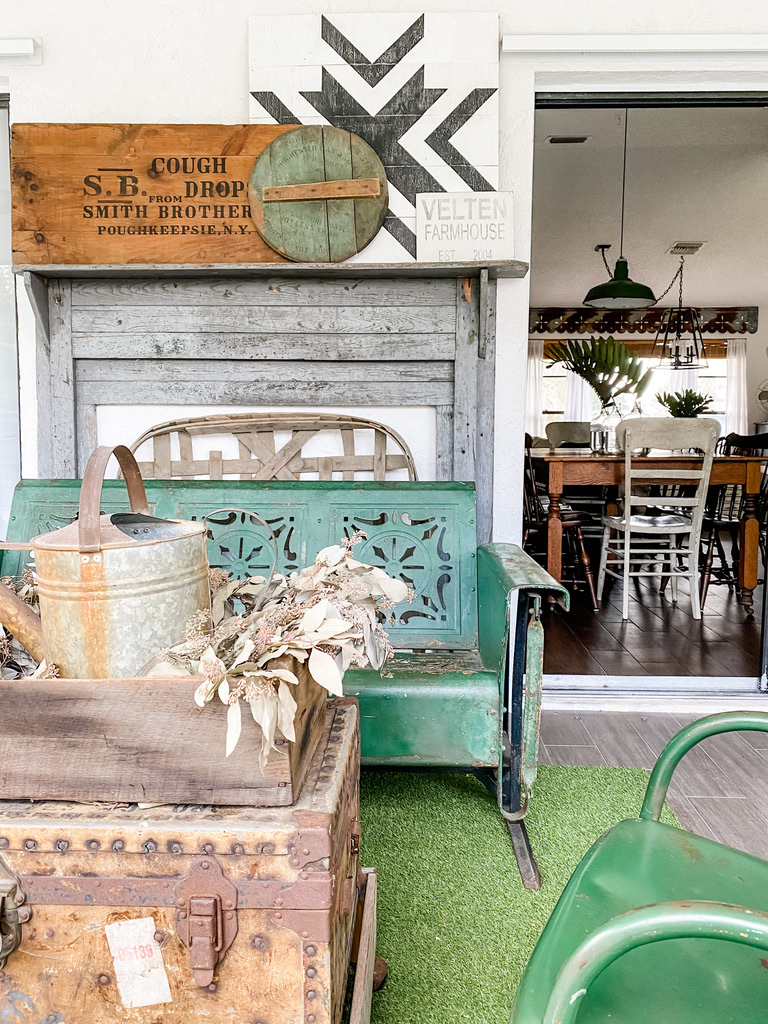 A military trunk repurposed as a coffee table in front of a vintage metal glider