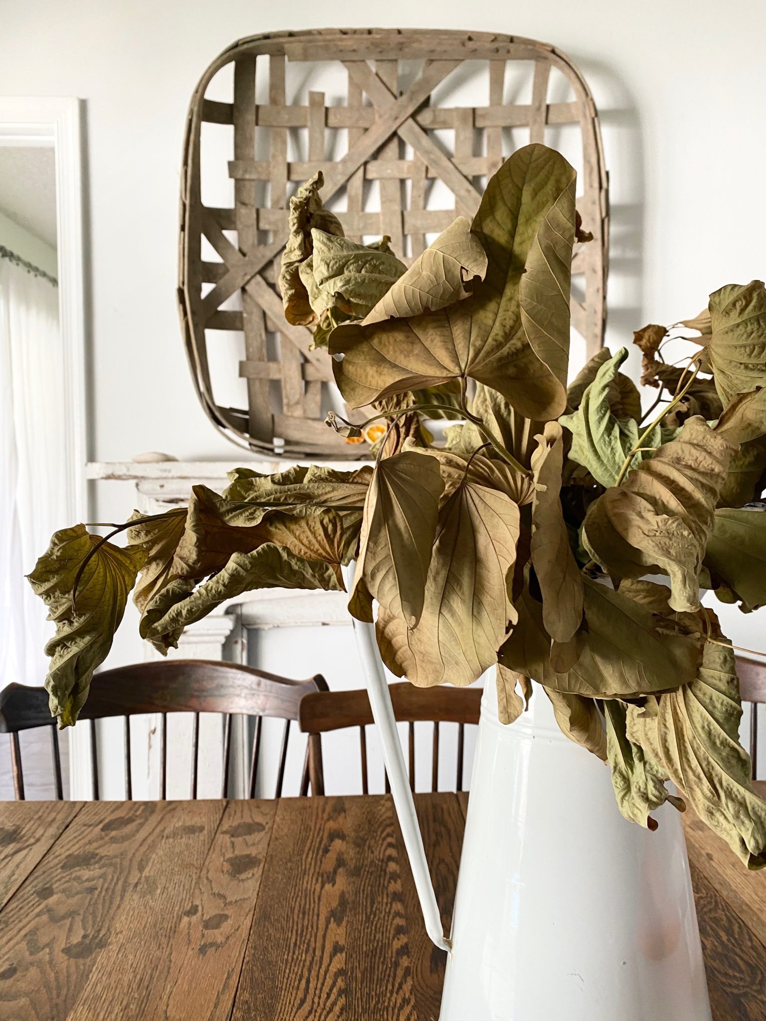 A tobacco basket on the wall above the chippy white mantel in the dining room.