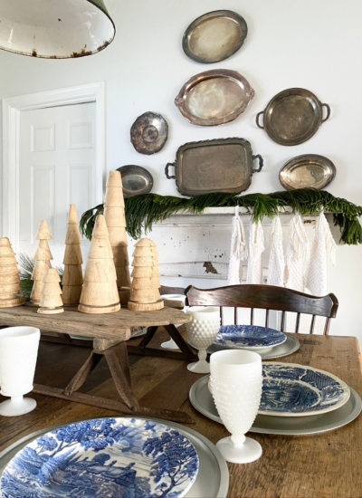 A Christmas Tablescape with a chippy holiday mantel in the background
