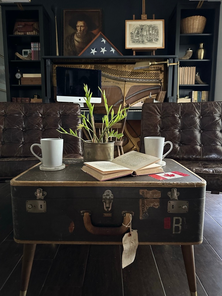 A full view of our black office nook complete with piano desk, bookshelves, and brown leather Barcelona chairs.